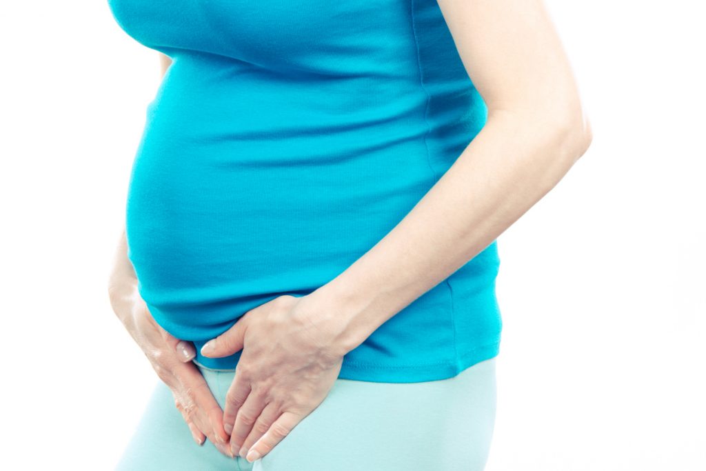 Pregnant woman with hands on her stomach, pregnancy health care and bladder aches 