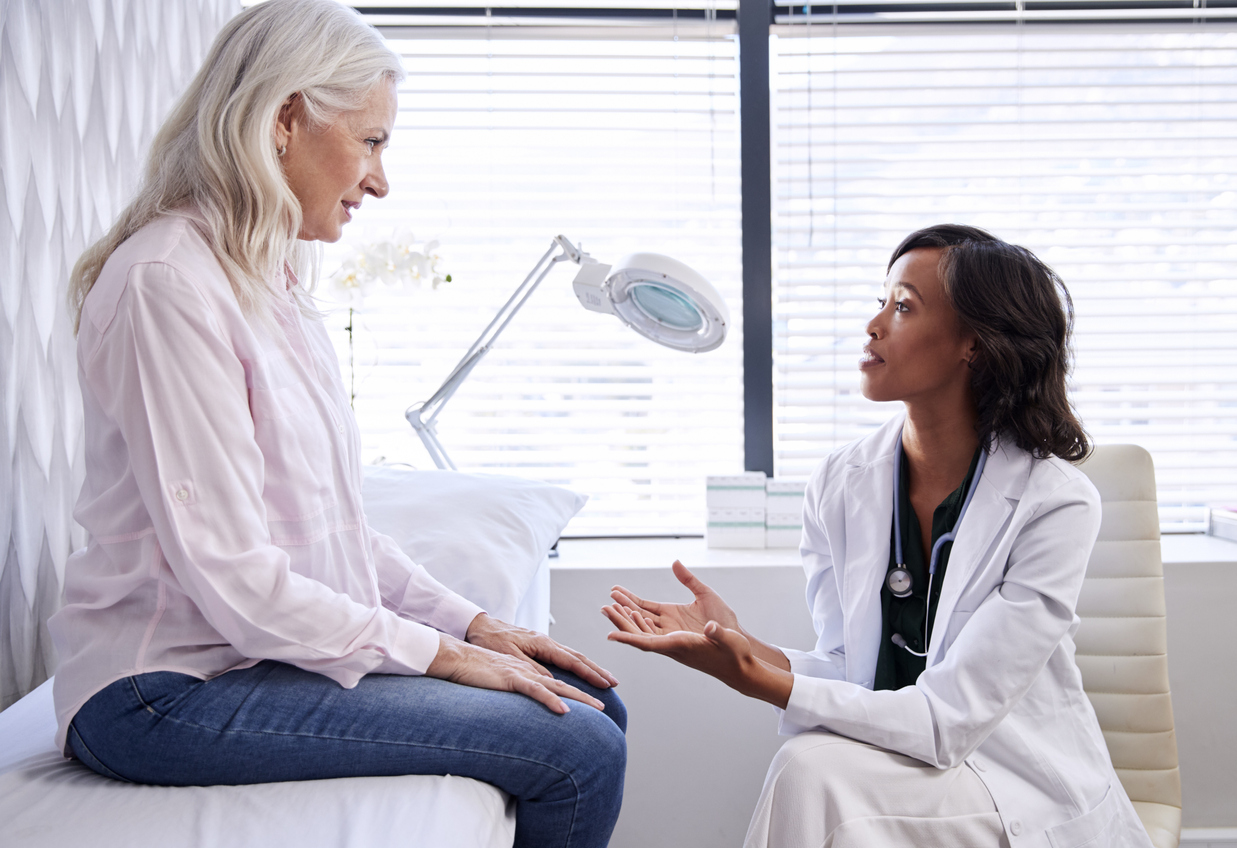 older woman in consultation with black female doctor in office